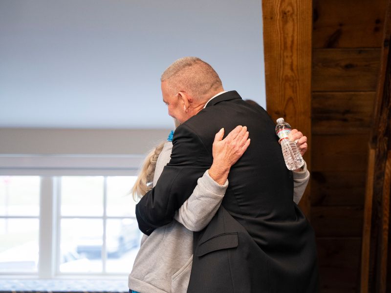 Guest Safety Coodinator Frank Jones embraces Dining Room Worker Crystale Strupp during commendation ceremony at Campus Safety Building.